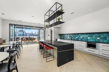 a kitchen with a long island with red chairs and white cabinets at Inspire West Town, CHICAGO
